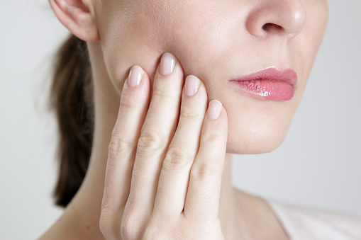 Woman pressing at her aching jaw at Solutions Dental Implants in Sun City West AZ 85375